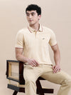 Man wearing a beige oat milk beige solid polo t shirt with pocket on a light gray background