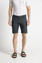 Person wearing dark gray shorts and a white polo shirt on a light background