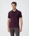 Man wearing a red birds eye engineered stripe polo with casual styling on a gray background
