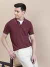 Man wearing a maroon solid polo t shirt with pocket with casual styling on a gray background