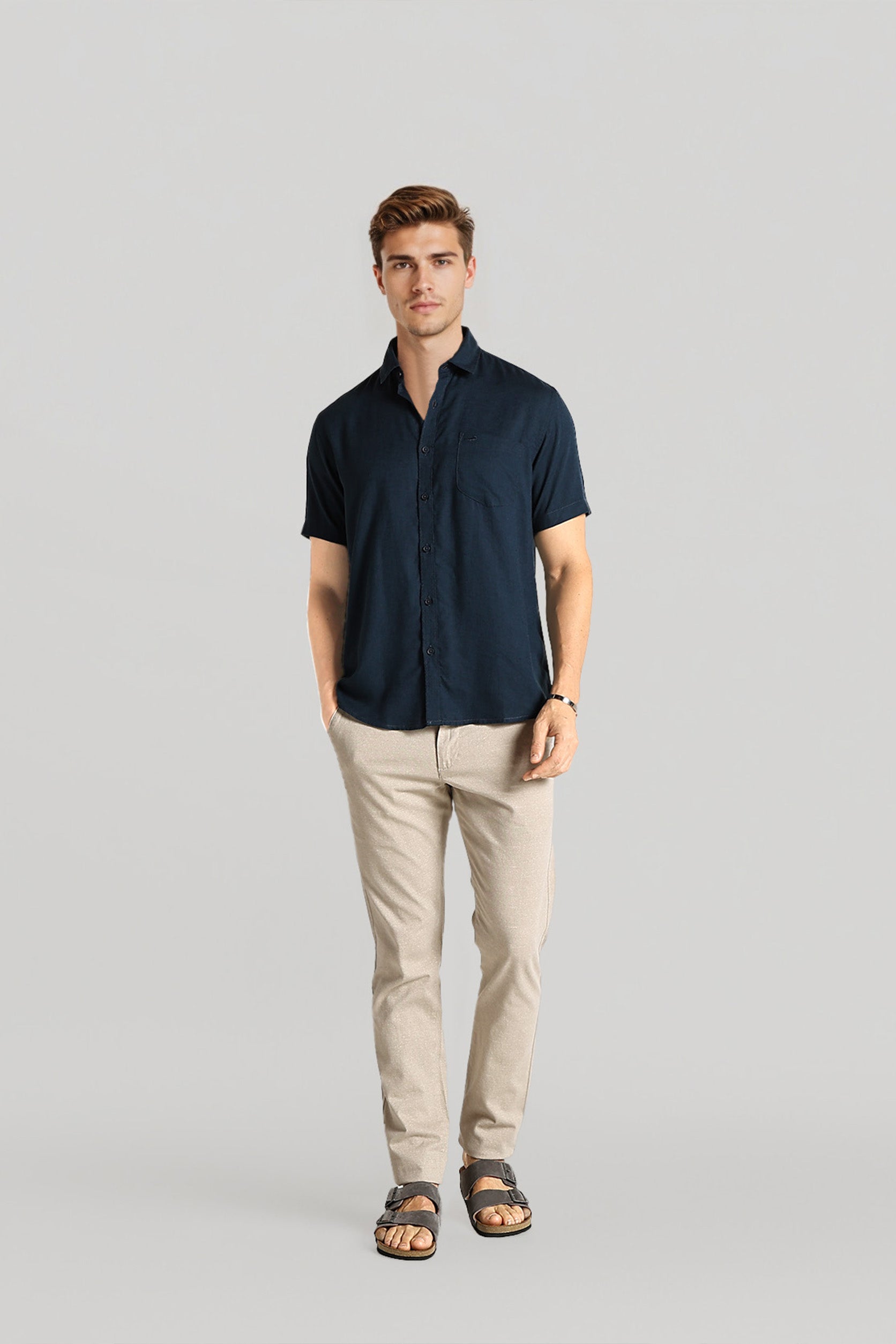 Man wearing a navy shirt and beige pants on a gray background