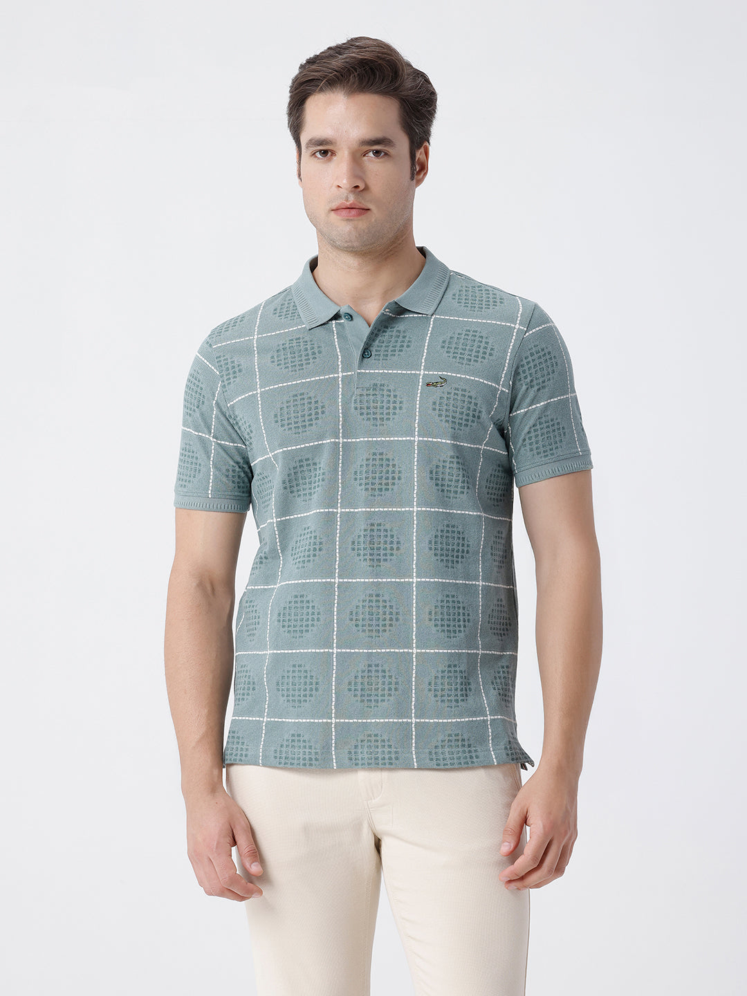 Man wearing a green checkered all over printed polo t shirt green with casual styling on a gray background