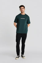 Man wearing a green t-shirt with 'CROODLE' logo on a light gray background