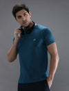 Man wearing a blue teal blue solid casual t shirt on a light gray background