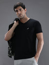 Man wearing a black black casual solid t shirt on a light gray background