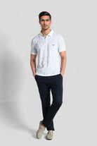 Man wearing a light gray polo shirt and dark blue pants on a white background