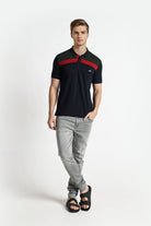 Man wearing a black and red polo shirt with gray pants on a white background