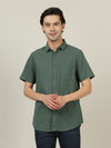 Man wearing a green green solid half sleeve linen shirt with casual styling on a gray background