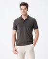 Man wearing a green birds eye engineered stripe polo green with casual styling on a gray background