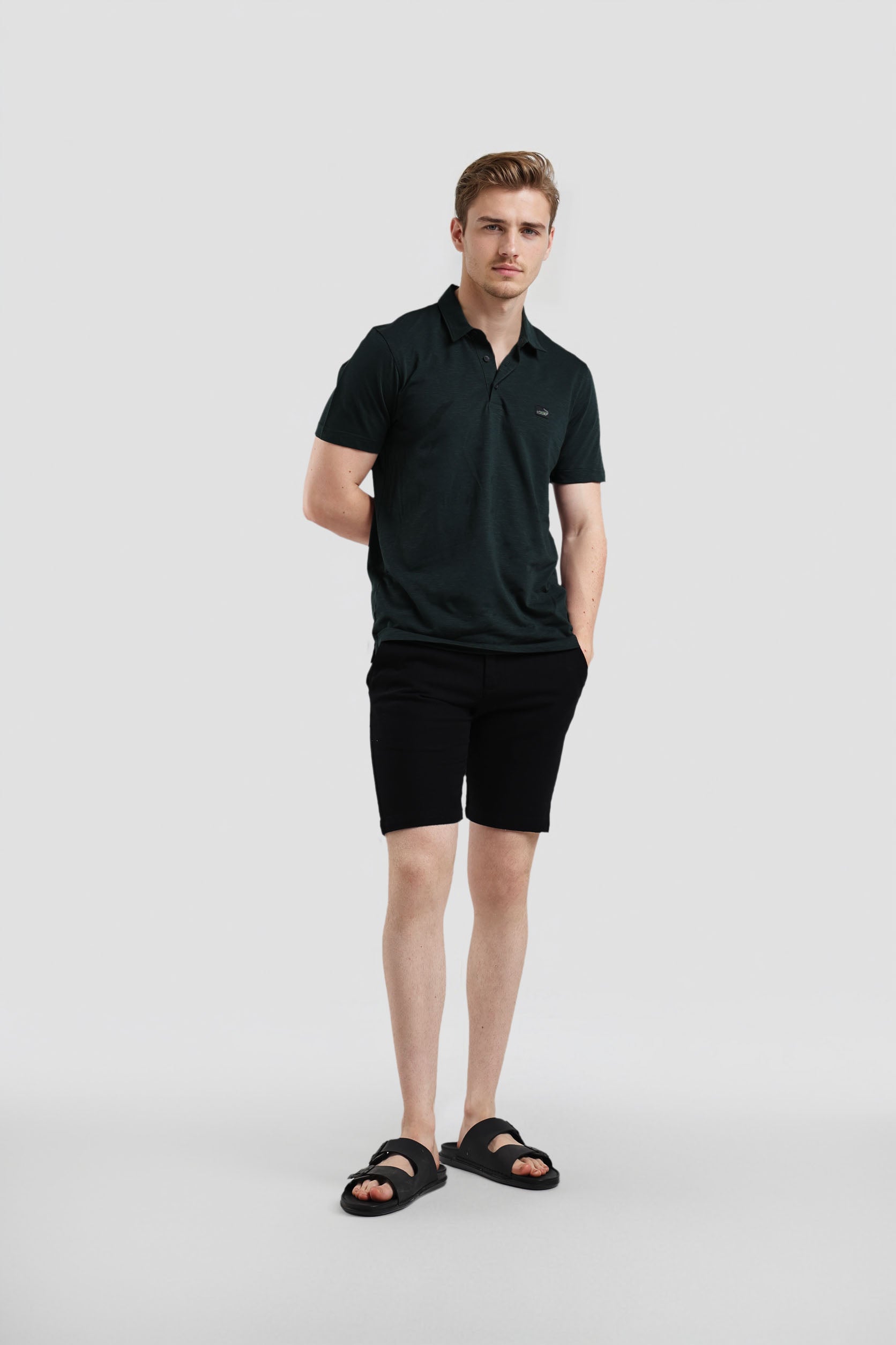 Man wearing a black polo shirt and shorts on a white background