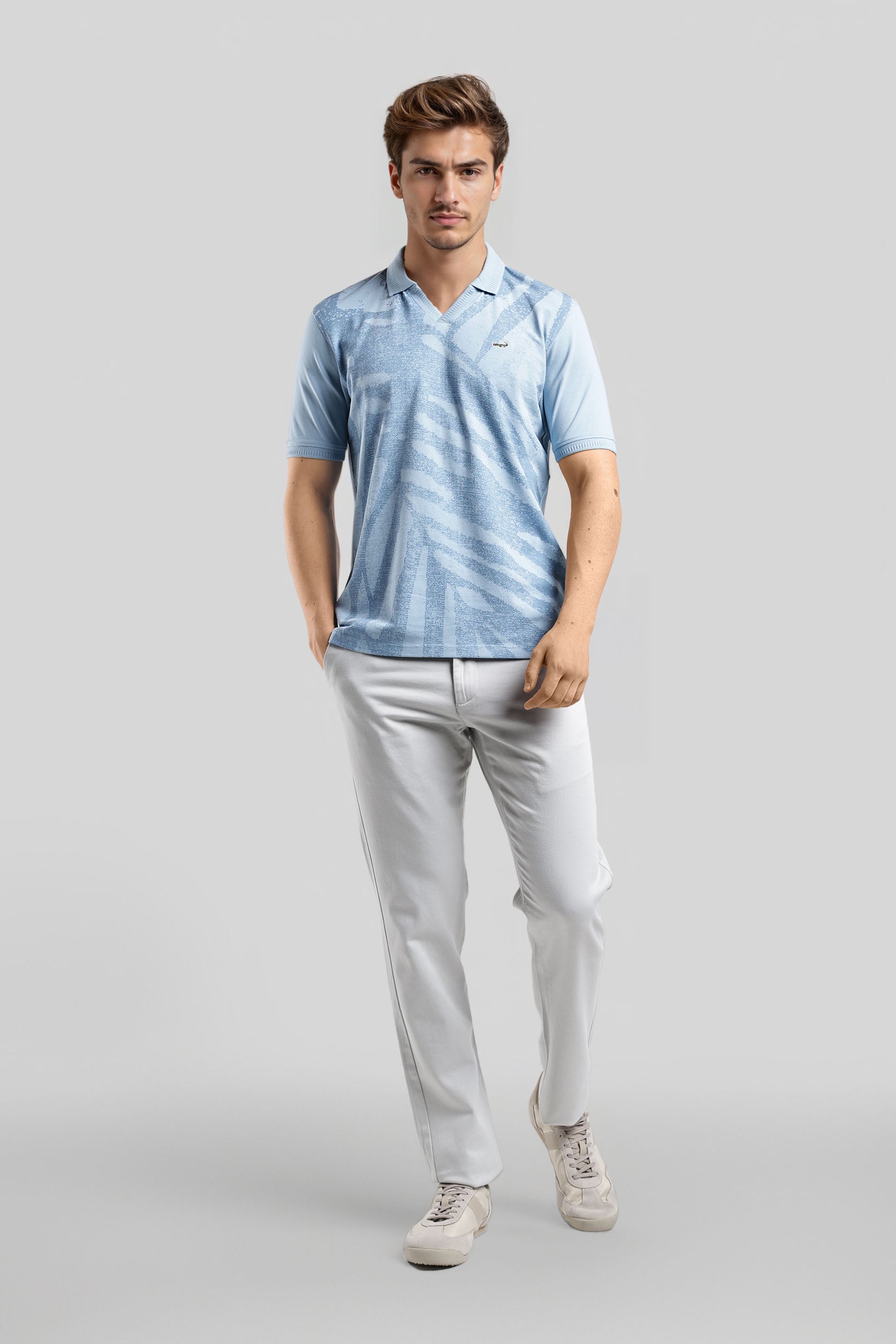 Man wearing a light blue striped polo shirt and white pants on a gray background