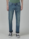 Man wearing a blue light blue solid mid rise slim fit casual jean on a light gray background