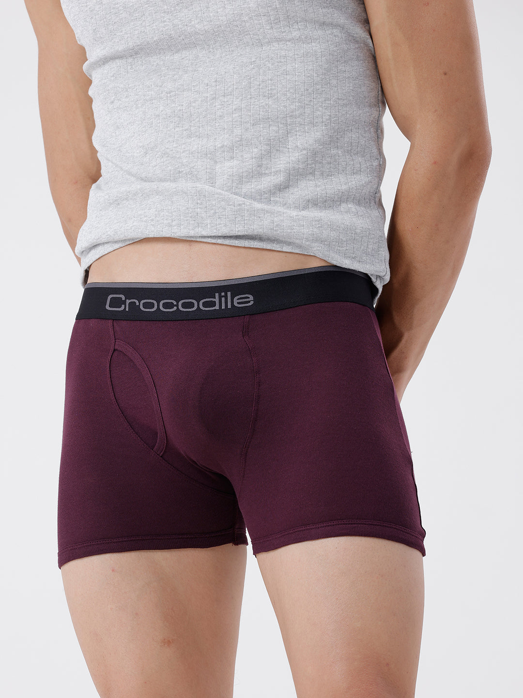 Person wearing maroon boxer briefs with a gray tank top on a white background
