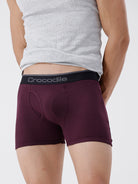 Person wearing maroon boxer briefs with a gray tank top on a white background