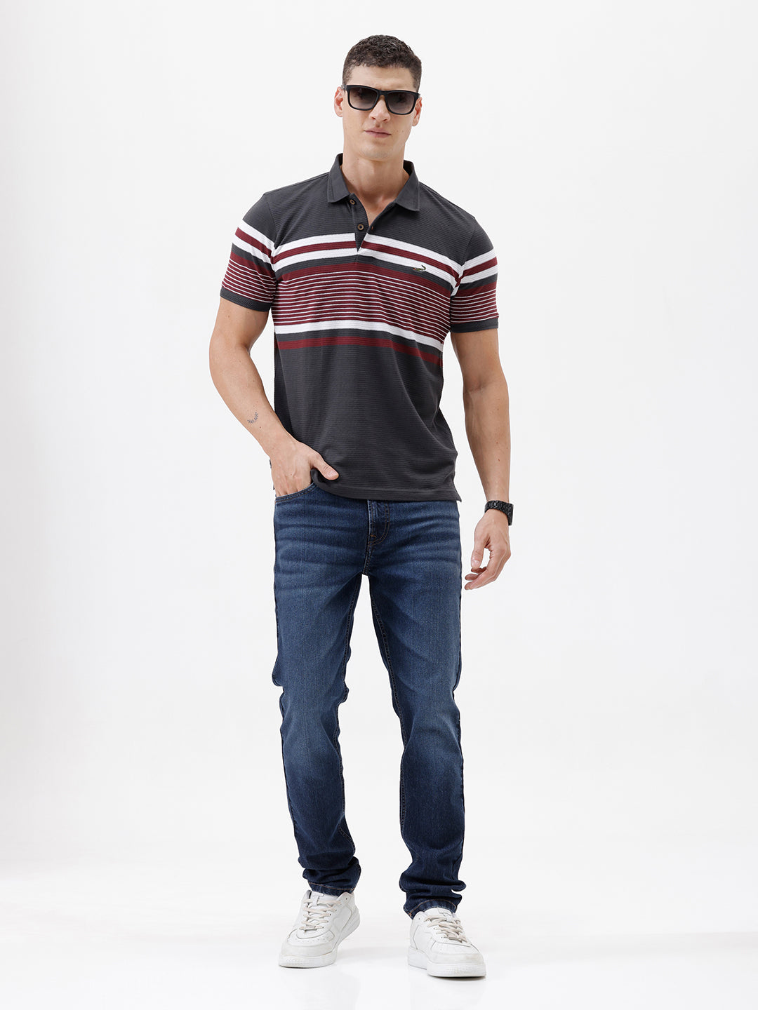 A person wearing dark blue slim-fit jeans with a faded wash, paired with a black t-shirt and white sneakers, shown from the waist down against a plain white studio background.