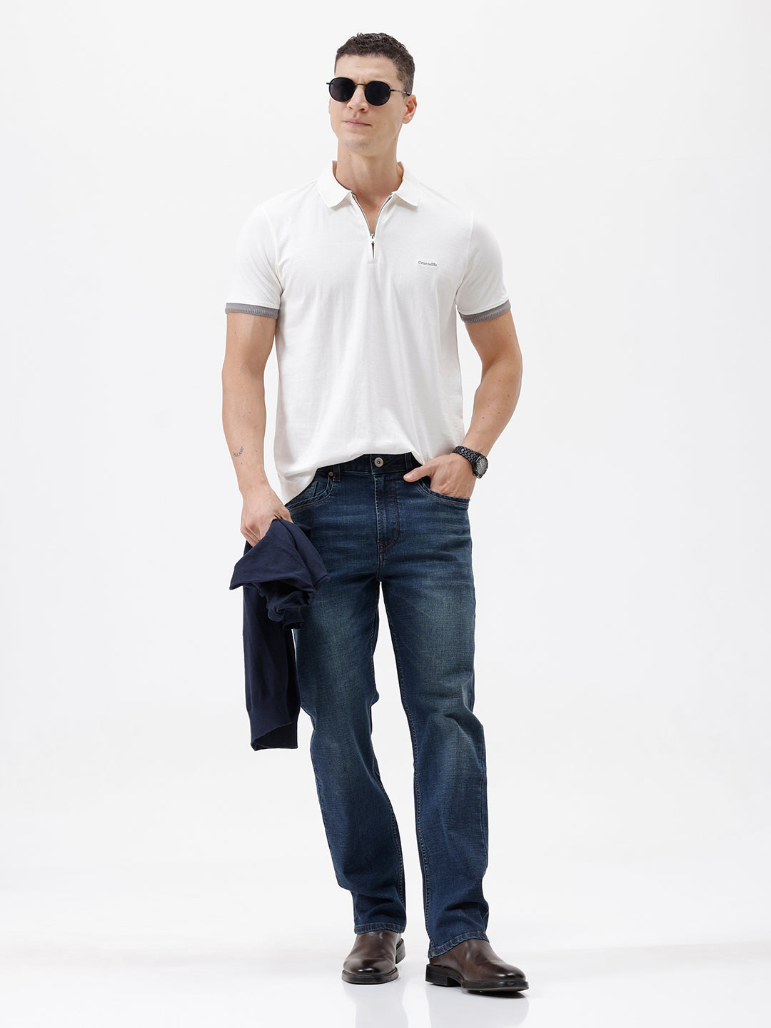 A man wearing a white short-sleeve polo shirt with gray ribbed trim on the collar and sleeve cuffs, paired with dark blue jeans, photographed against a plain white studio background.
