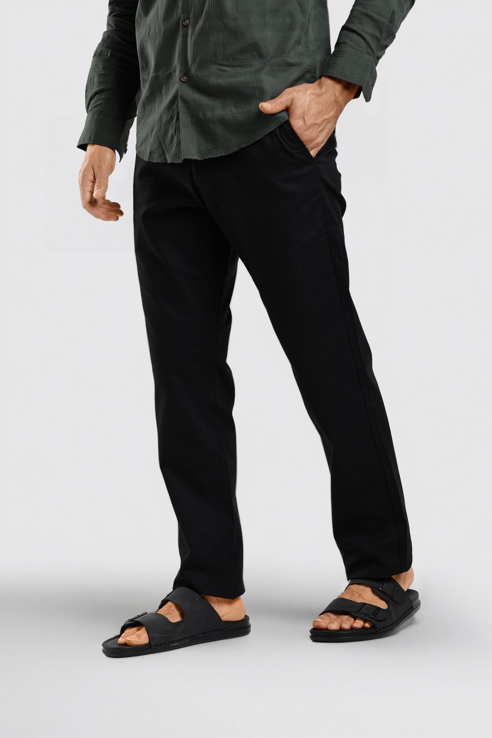 Person wearing black pants and sandals on a white background