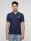 Man wearing a navy blotch pattern all over printed polo t shirt in navy on a light gray background