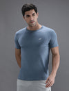 Man wearing a blue solid sport fit blue t shirt with casual styling on a gray background