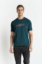 Man wearing a teal t-shirt with red text on a white background