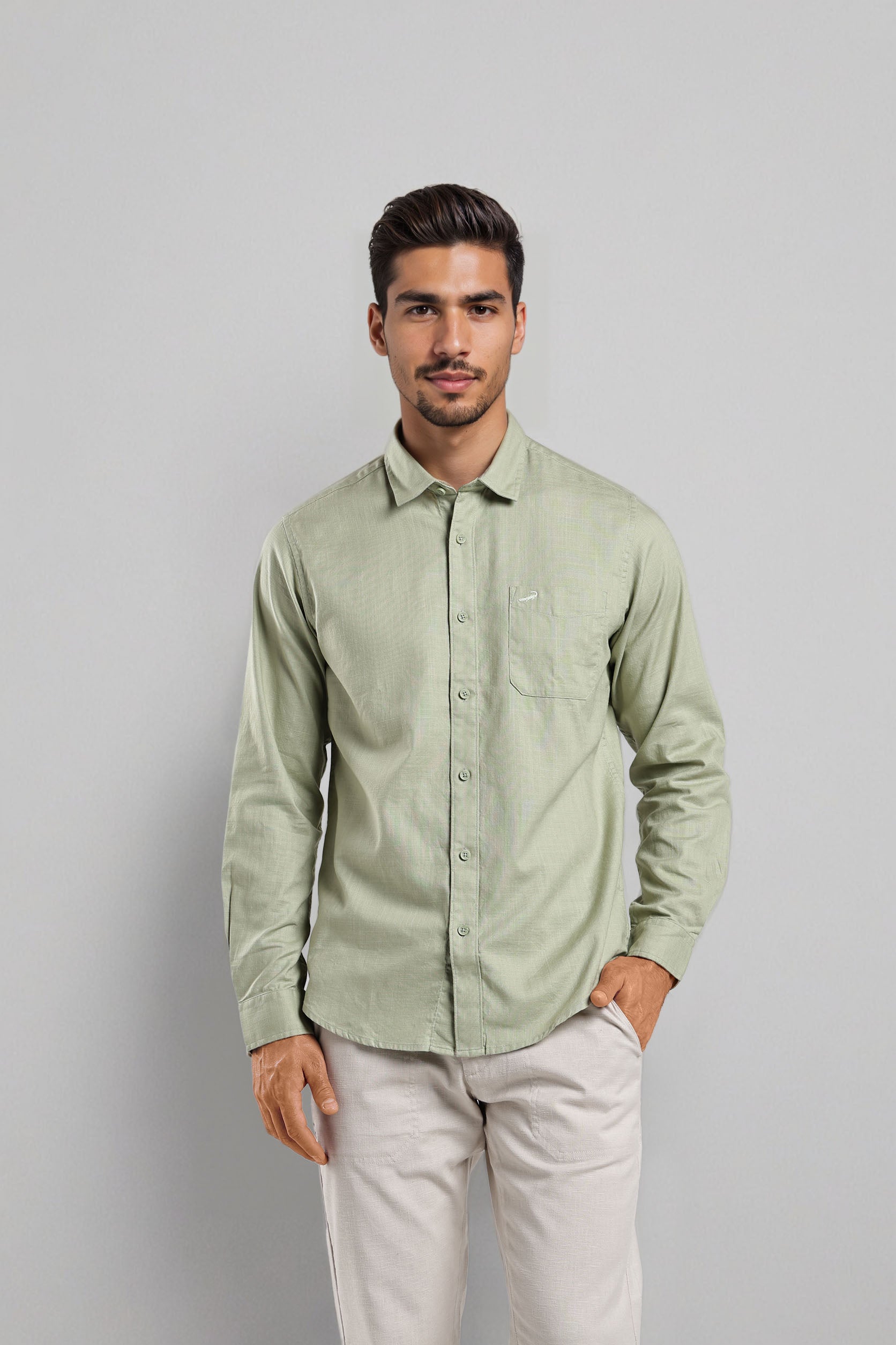 Man wearing a light green shirt and white pants against a gray background