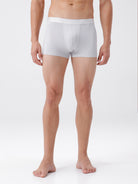 Man wearing white boxer briefs on a plain background