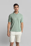 Man wearing a green green solid polo t shirt slim fit polo t shirt on a light gray background