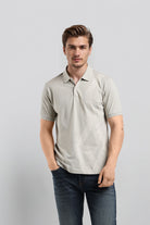 Man wearing a light gray polo shirt with a subtle pattern on a plain background