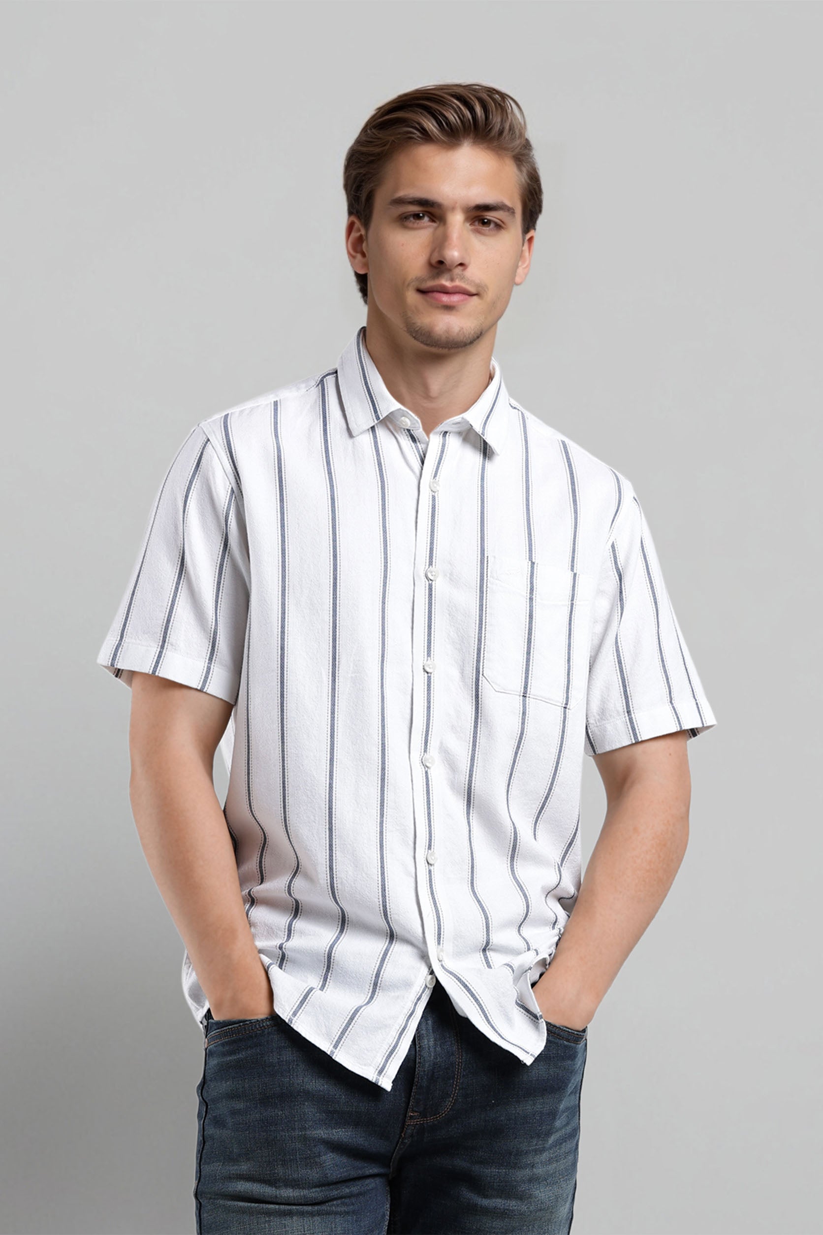 Man wearing a white striped shirt and dark jeans against a gray background