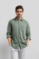 Man wearing a green patterned shirt and white pants on a light gray background