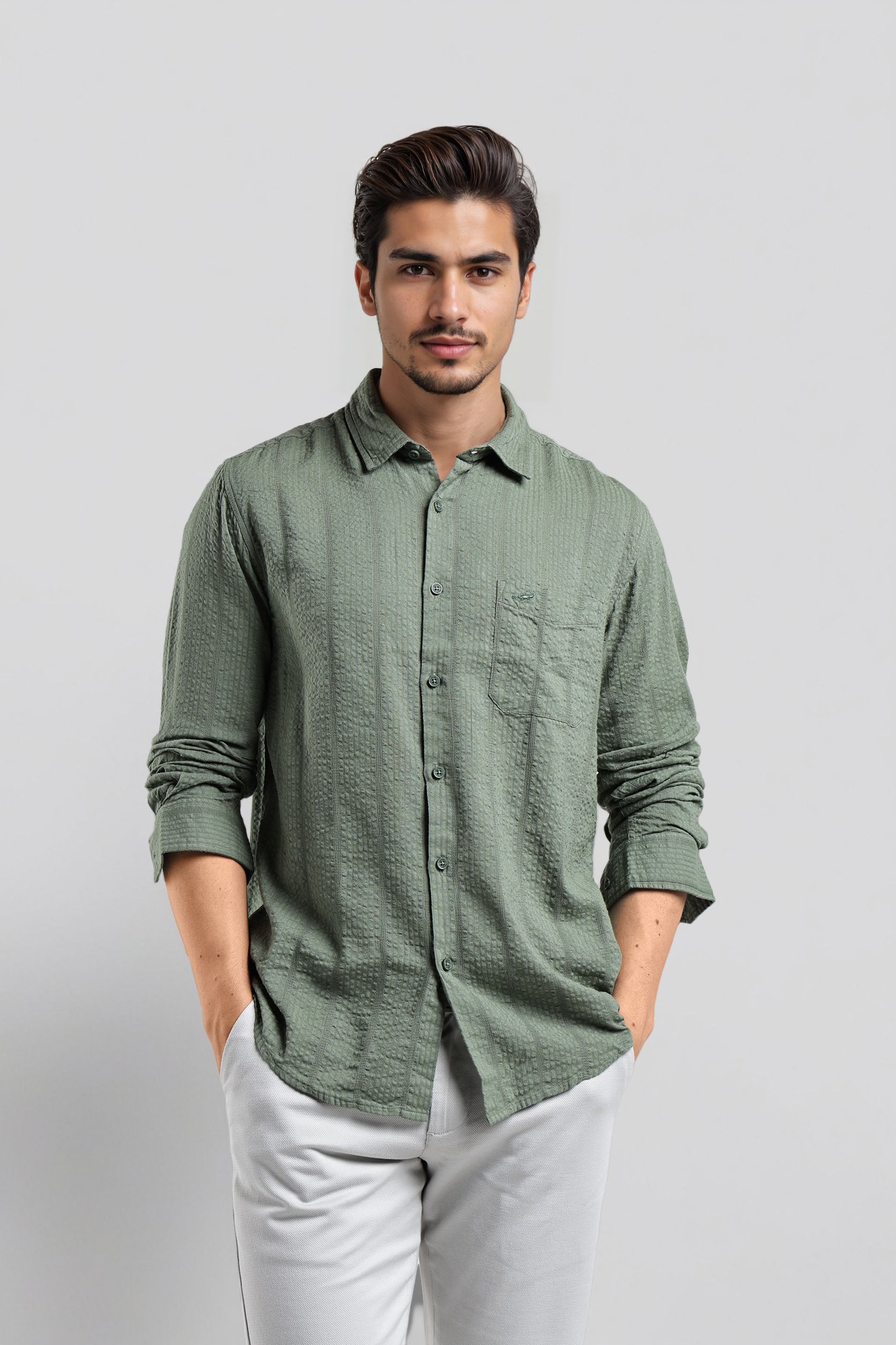 Man wearing a green patterned shirt and white pants on a light gray background