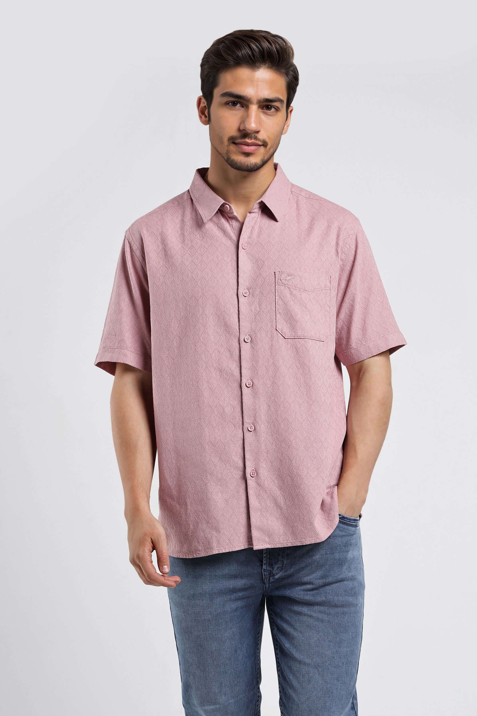 Man wearing a pink short-sleeve shirt and blue jeans on a white background