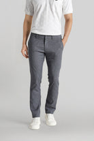 Person wearing gray pants and a white shirt on a plain background