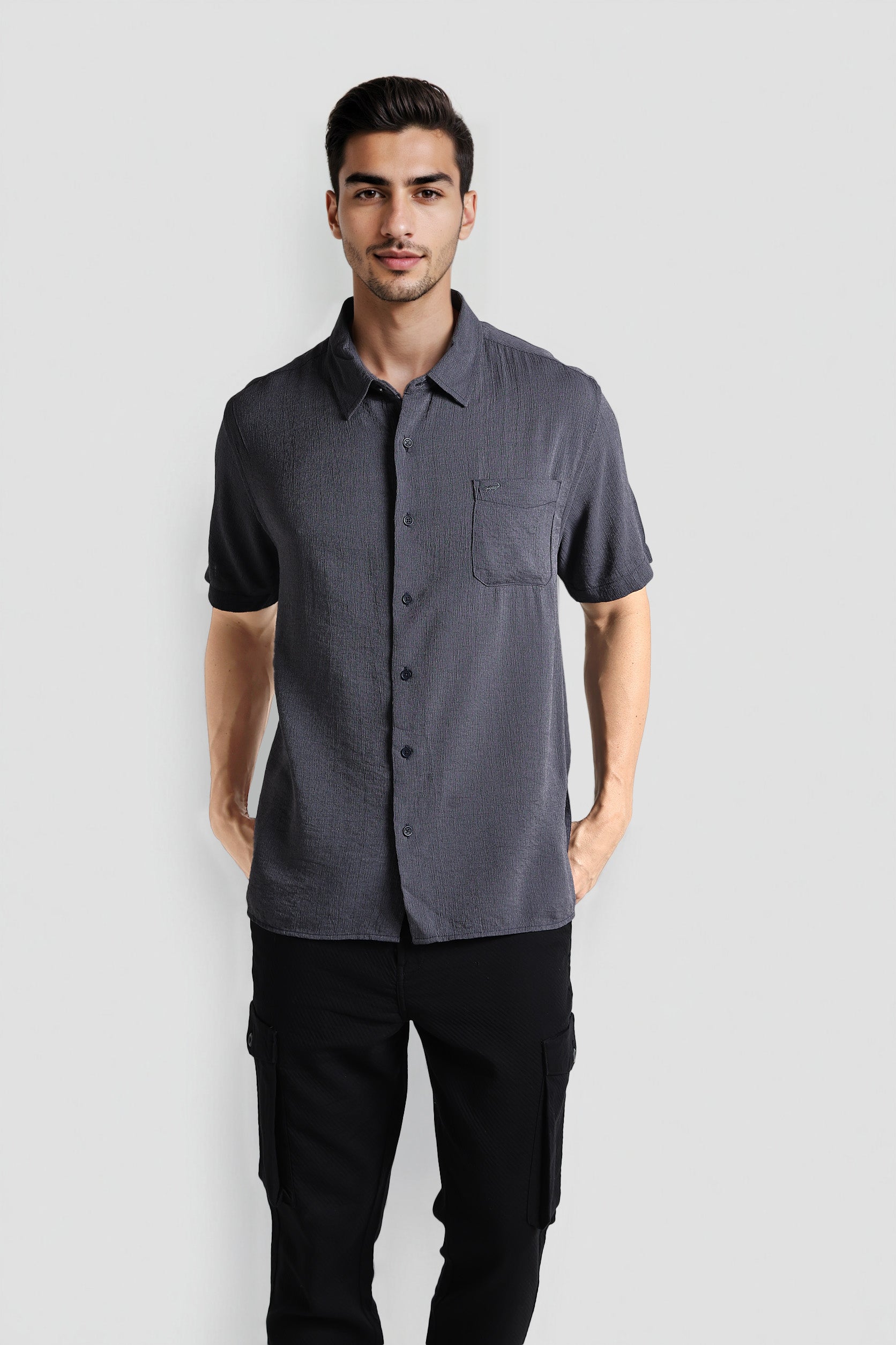 Man wearing a gray short-sleeve shirt and black pants on a white background