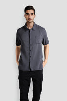 Man wearing a gray short-sleeve shirt and black pants on a white background