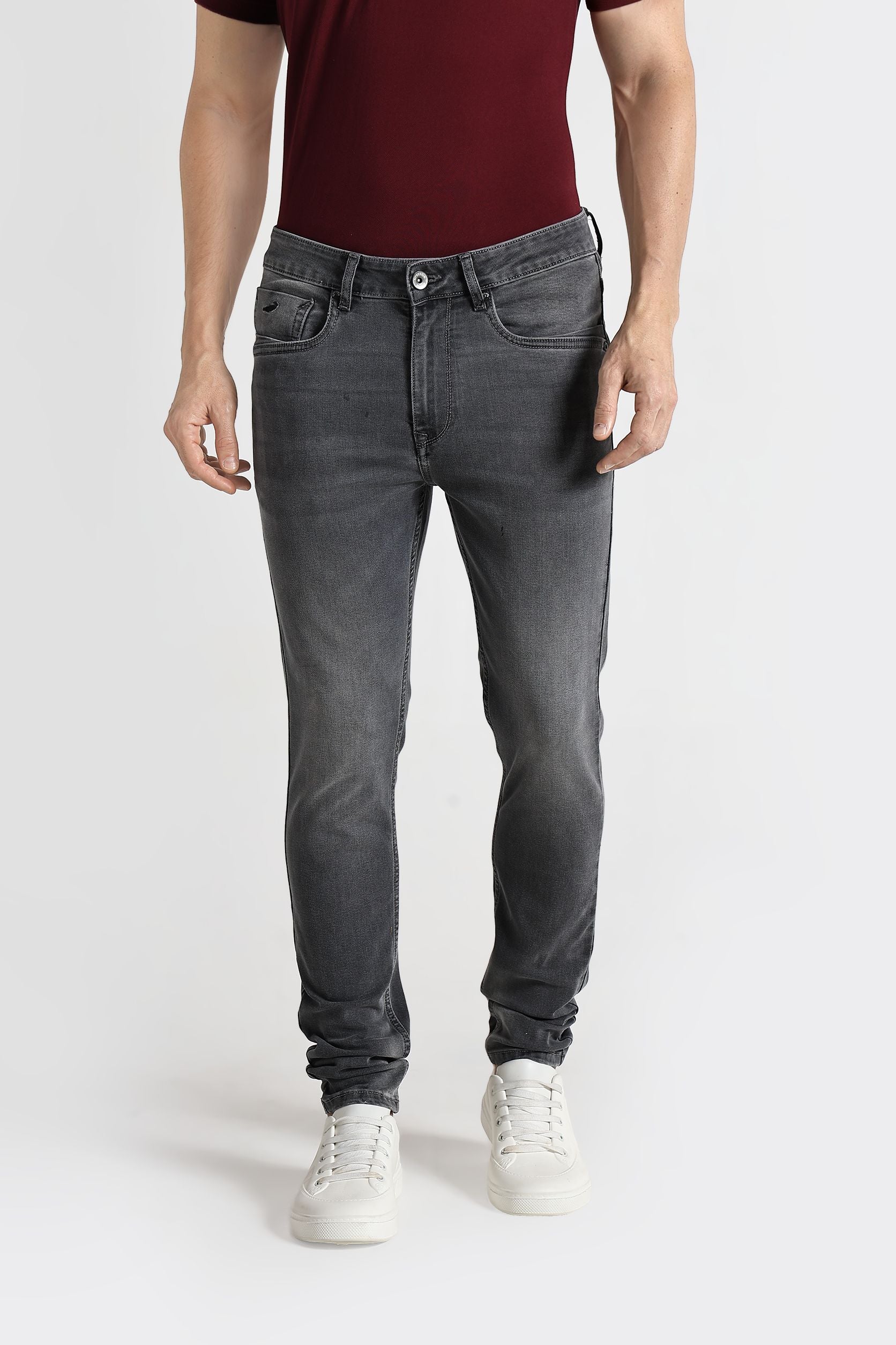 Person wearing gray jeans and a maroon shirt on a white background