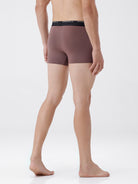 Person wearing brown boxer briefs on a white background