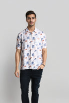 Man wearing a patterned shirt and dark pants on a plain background