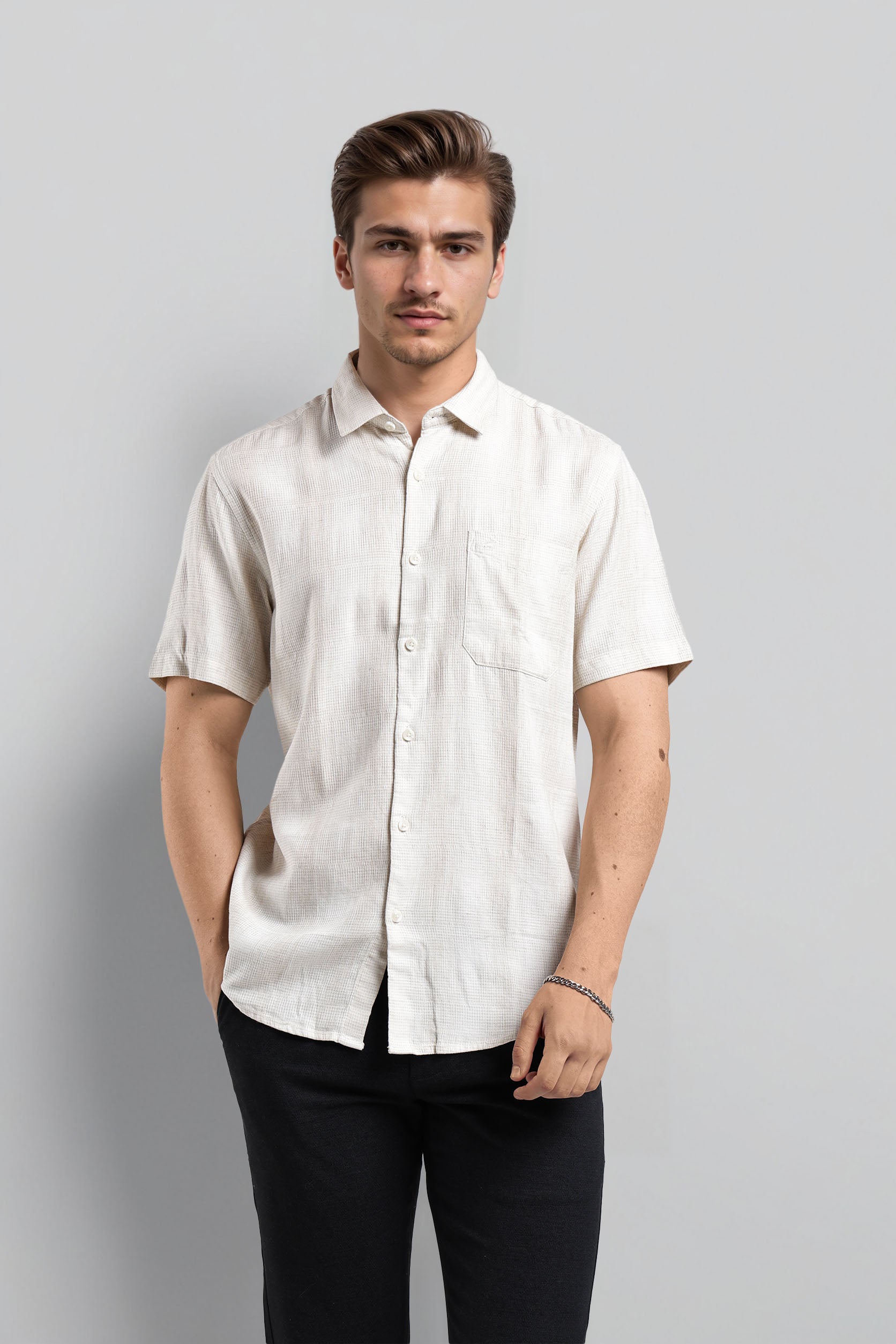 Man wearing a white short-sleeve shirt against a gray background