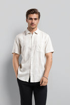 Man wearing a white short-sleeve shirt against a gray background