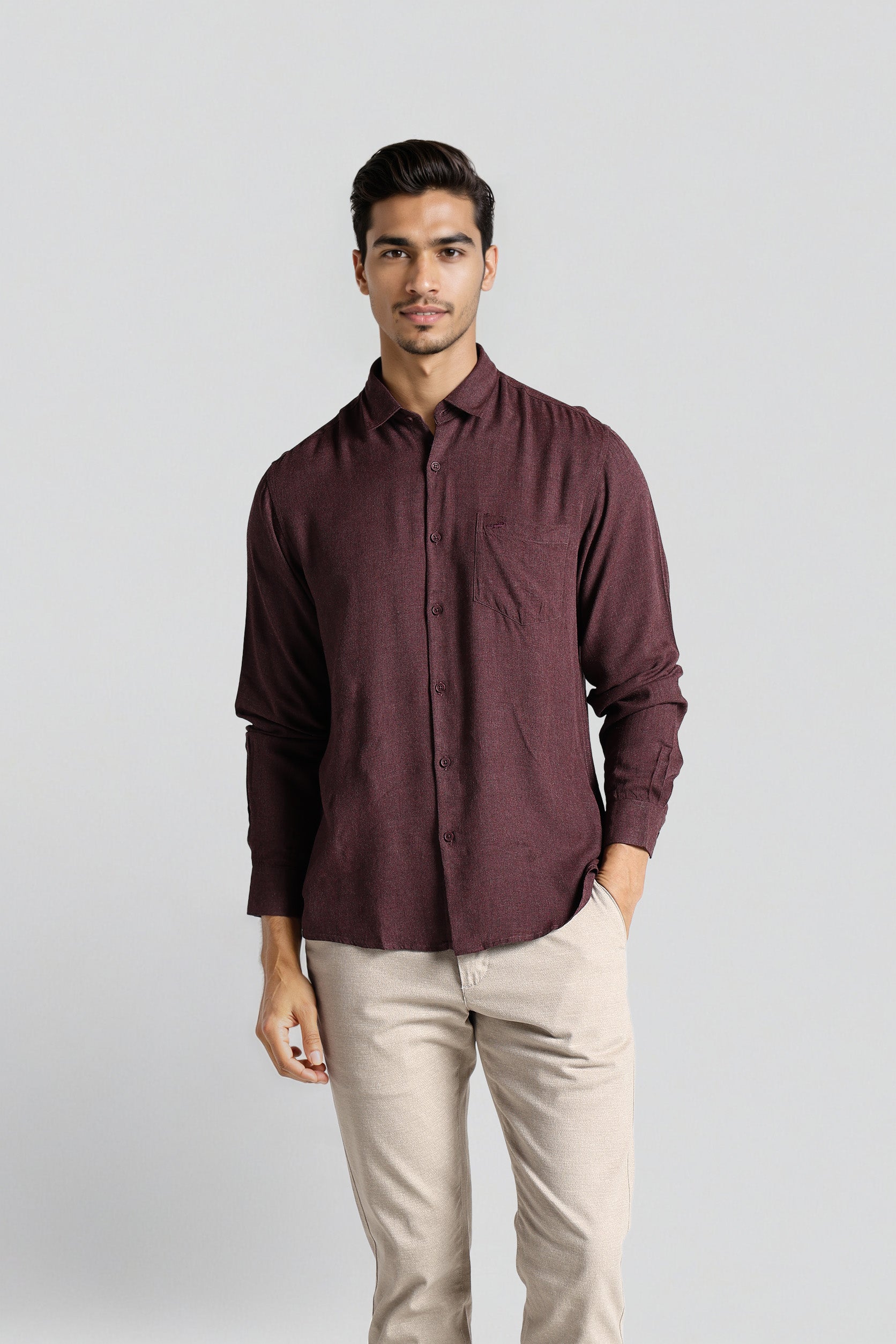 Man wearing a maroon shirt and beige pants on a light gray background