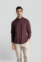 Man wearing a maroon shirt and beige pants on a light gray background