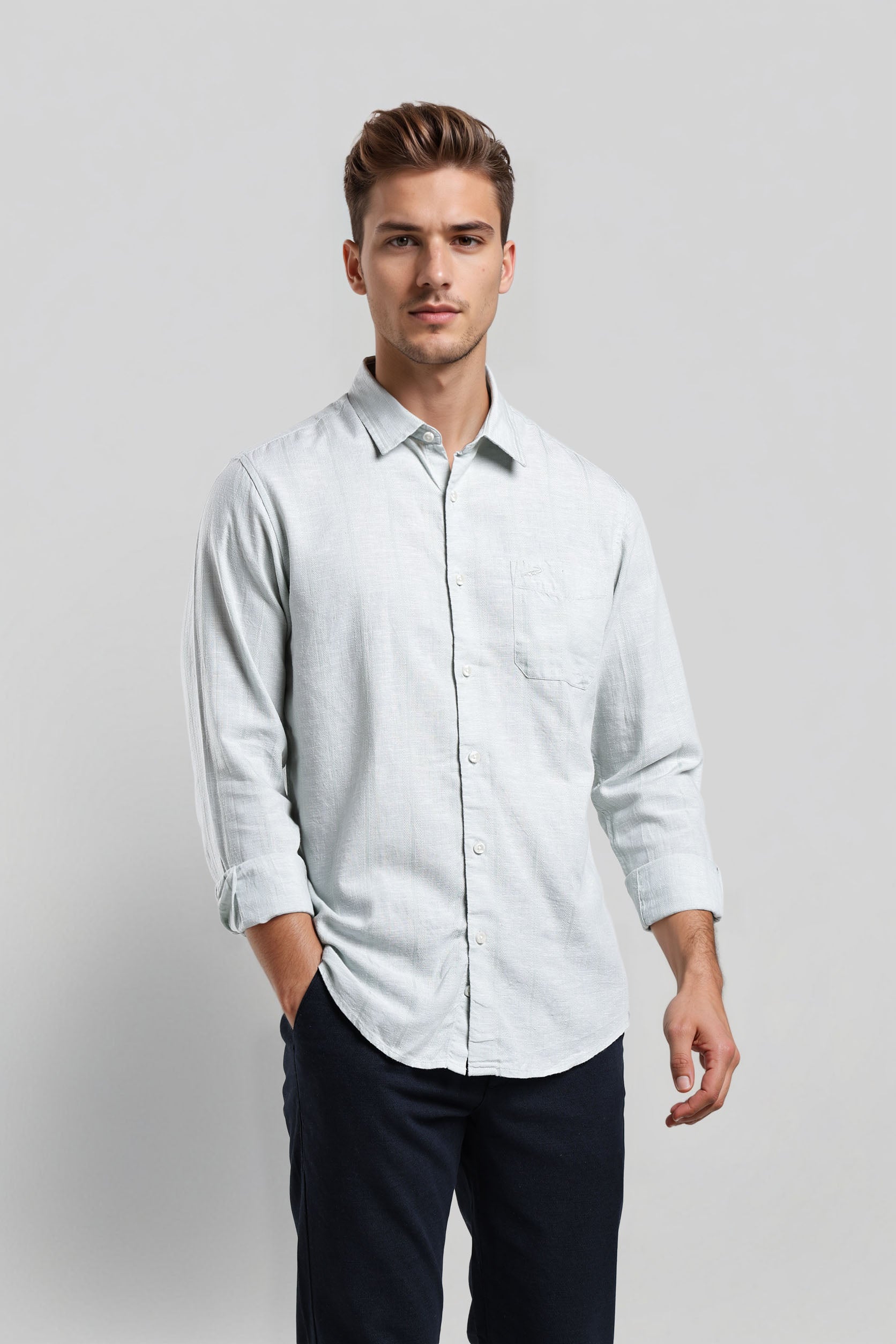 Man wearing a light blue shirt and dark pants on a plain background