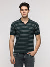 Man wearing a green popcorn jaquard striper polo t shirt in green with casual styling on a gray background