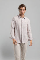 Man wearing a light-colored shirt and pants on a gray background