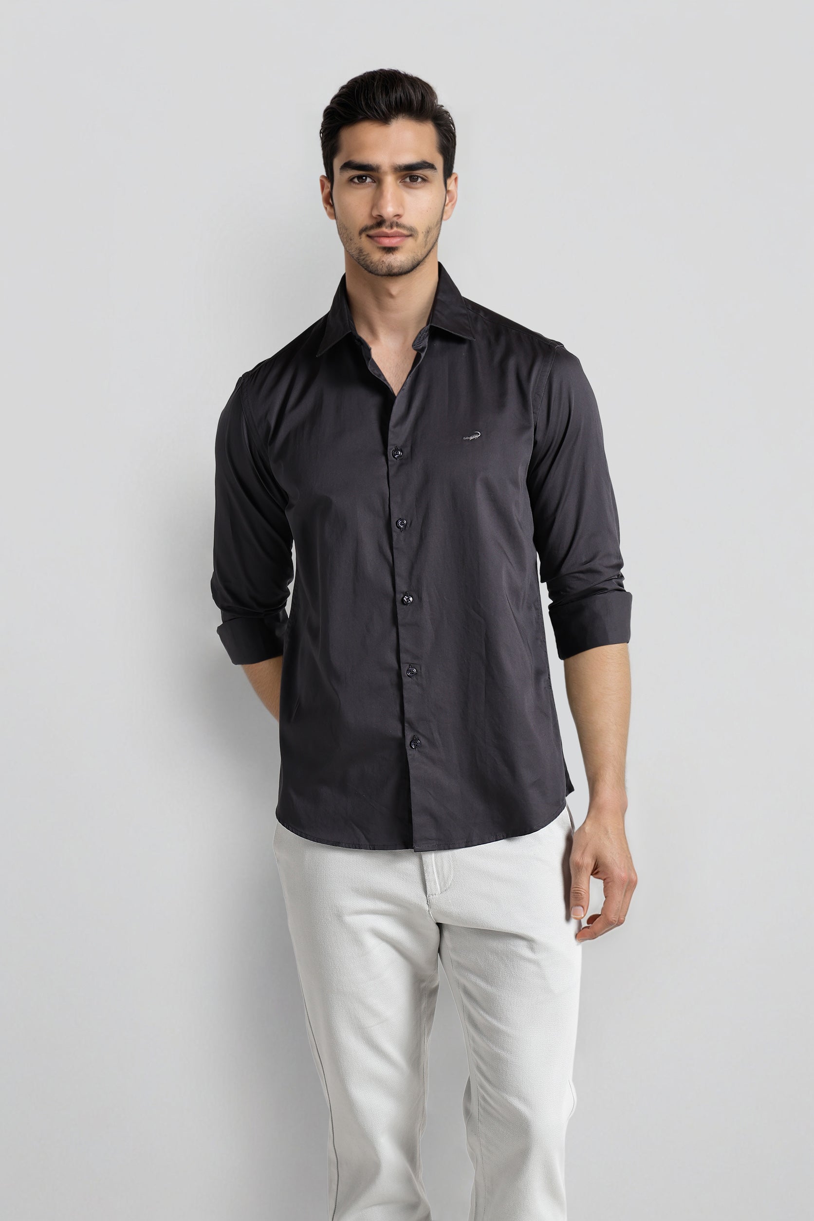 Man wearing a black shirt and white pants on a light gray background