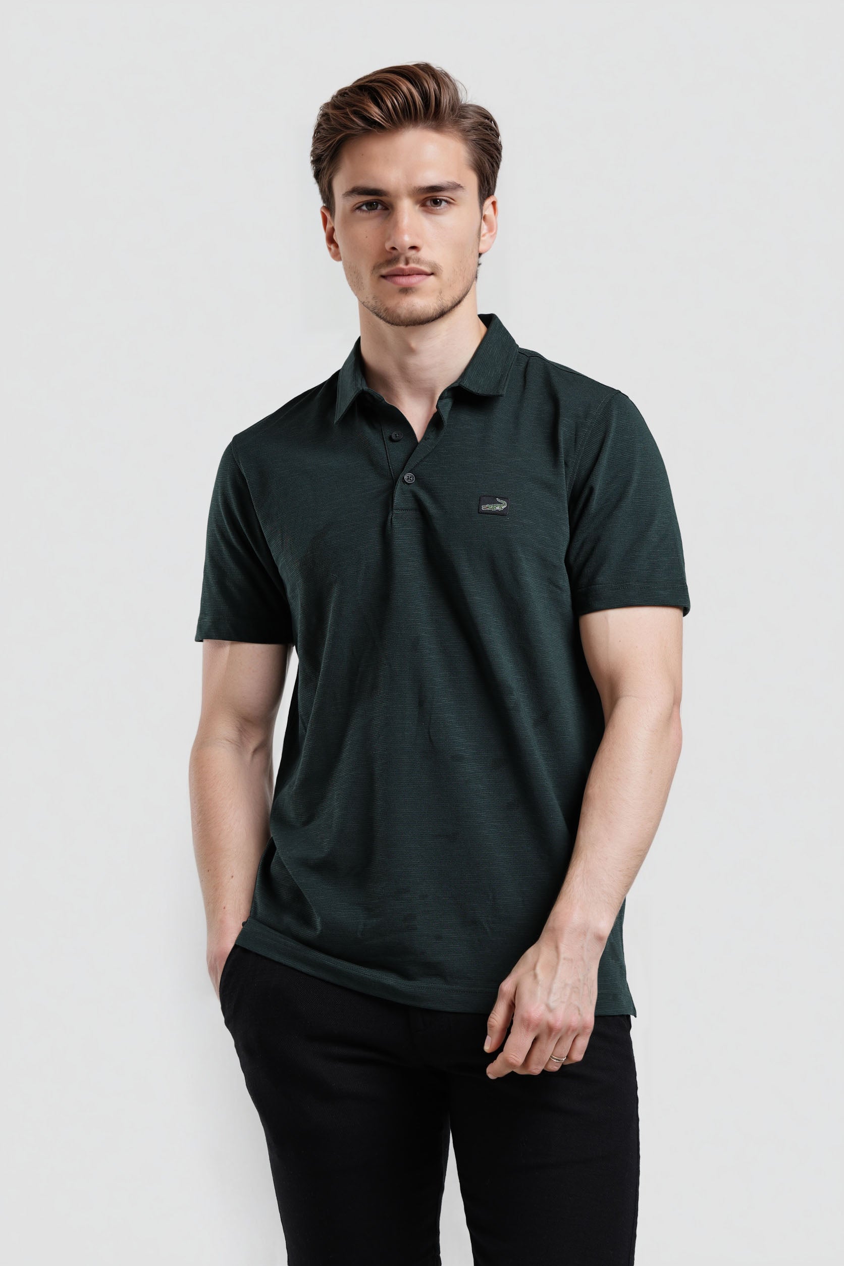 Man wearing a dark green polo shirt on a light gray background