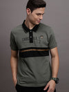 Man wearing a green deep lichen green colourblocked polo t shirt with casual styling on a gray background