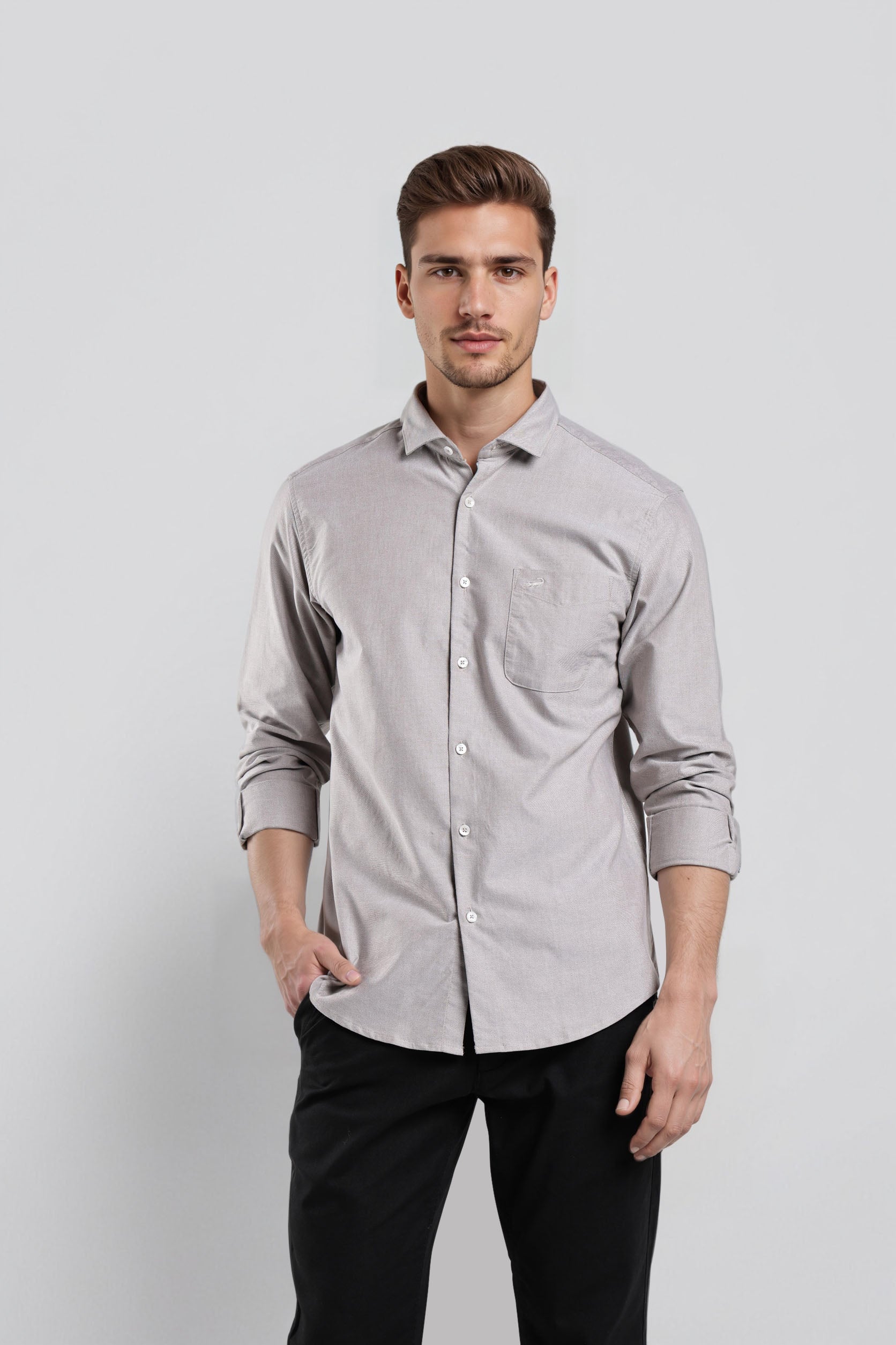 Man wearing a light gray button-up shirt and black pants against a white background