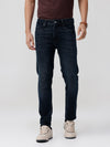 Man wearing a dark indigo knit slim fit jeans on a light gray background